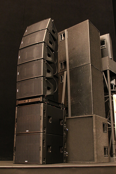 舞台下手にグラウンドスタックされた「NEXO GEO  M1012」×5、「NEXO MSUB15」×2、効果音再生用のサブウーファー「Meyer Sound 650P」。「650P」の上に設置されているのはフォールドバックスピーカーの「Meyer Sound MSL-4」×2とその奥に同「UPA-2P」