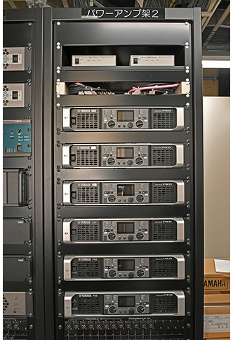 最適な環境を維持するアンプ室に整然と並ぶ機器架群。写真左＝「SHURE」の4chワイヤレス受信機「ULXD4Q」、「ヤマハ」のI/Oラック「Rio1608-D2」、さまざまな入出力がスムーズに行なえるよう考えられたパッチ盤などが収納されたラック。写真中＝デジタルマルチプロセッサー「MRX7-D」、「AFC3」システムおよび残響付加プロセッサー「LAP3-AFC」、メインスピーカーを駆動する「NEXO NXAMP4×2　MK2」パワーアンプが収納されたラック。写真右＝サラウンドスピーカー用のパワーアンプ「ヤマハPX8」